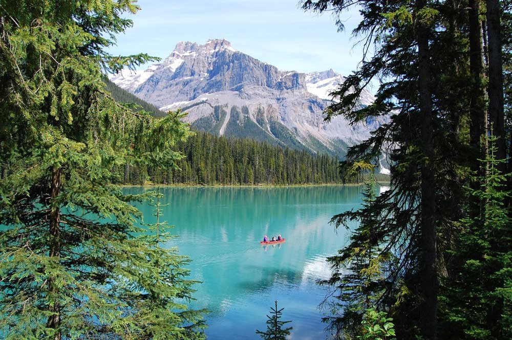 fotografía de un lago con el agua cristalina y detrás una montaña nevada